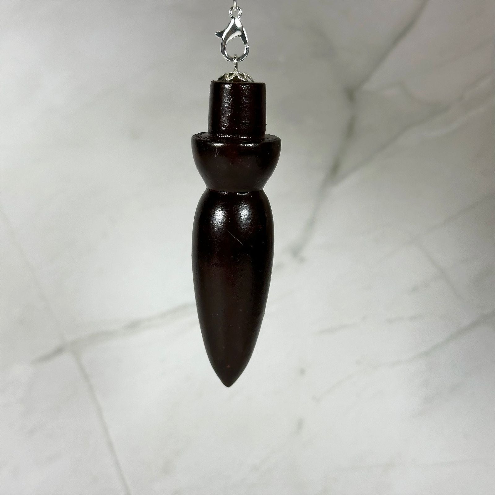 Pendule 7 chakras en bois de rose - Aeternum - a black and white vase on a white wall  - # boutique ésoterisme# - #wicca# 